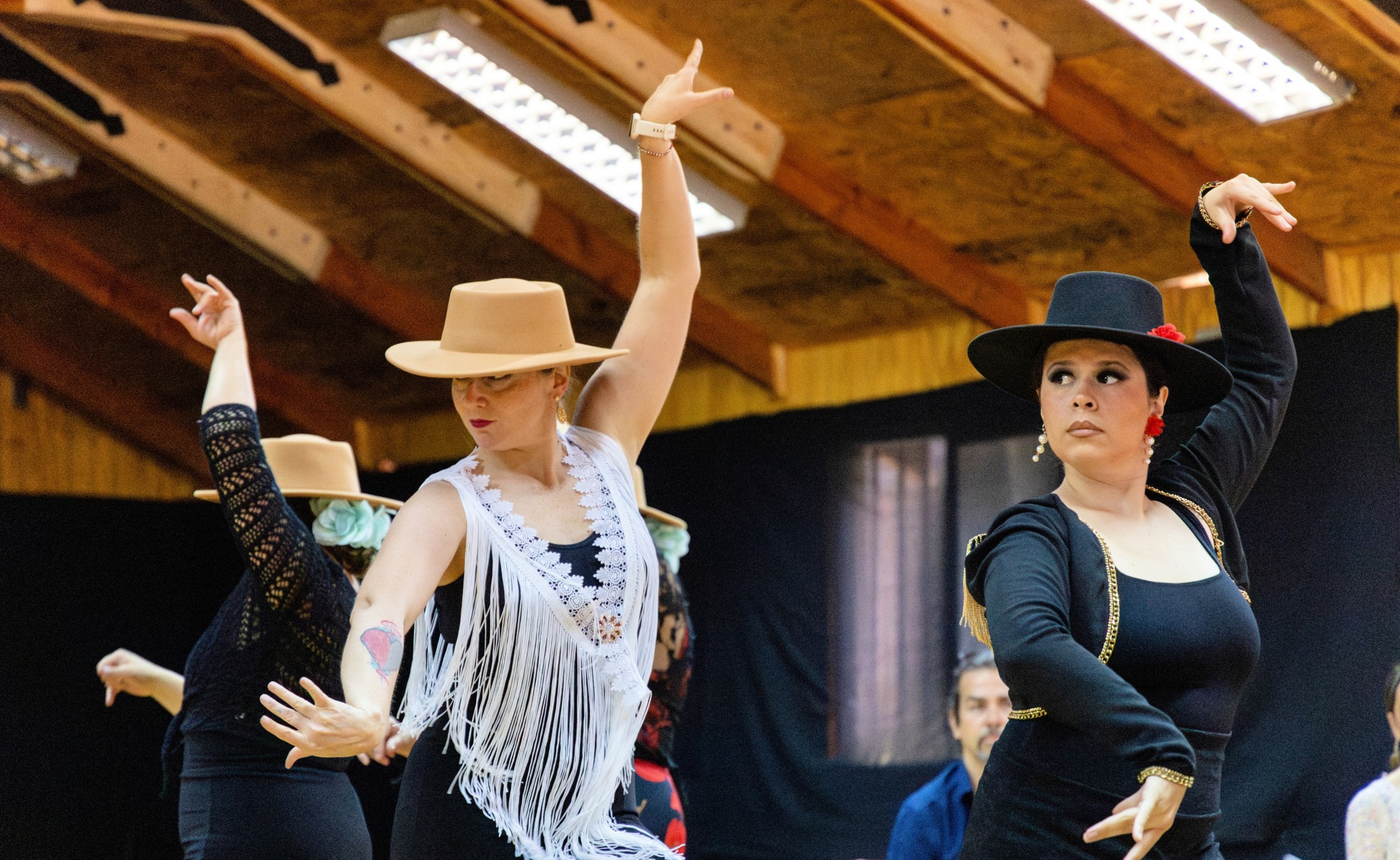 Alumnas en escena con vestidos de flamenca dorados, en formación