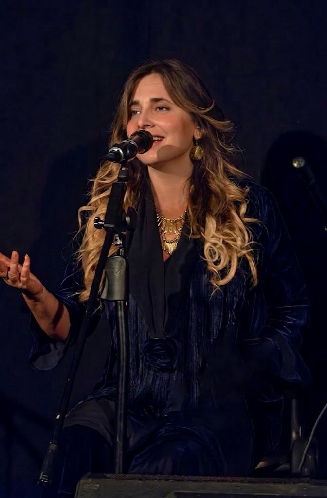 Jazmín cantando flamenco al micrófono con chaqueta azul terciopelo