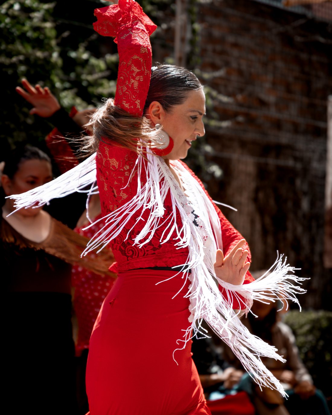 Paola Peñailillo bailando flamenco con vestido rojo y mantón de flecos blancos